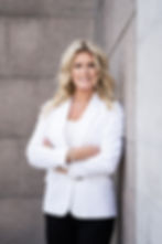 Beth Blackmore in white blazer leaning against stone building