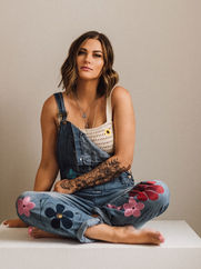 Catie St. Germain sitting cross legged in overalls