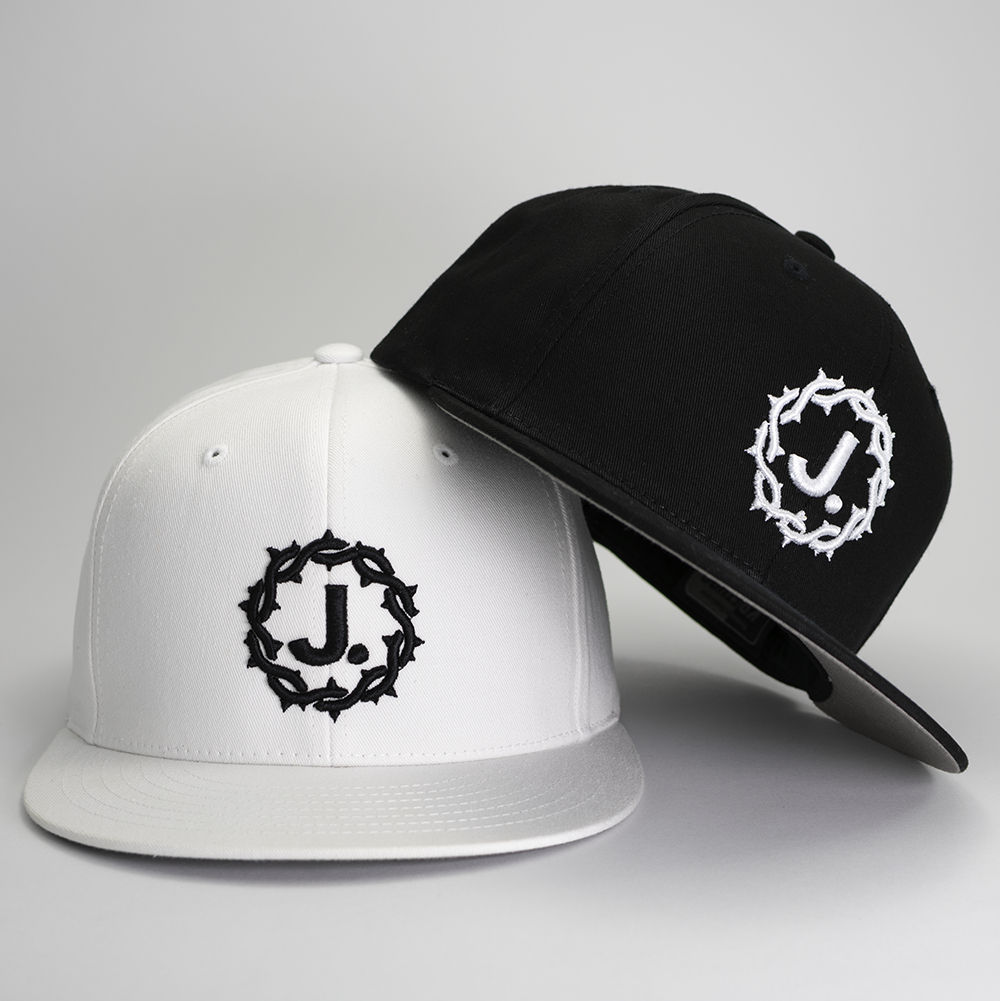 Black and white wool snap back baseball caps with embroidered J. crown of thorns logo.