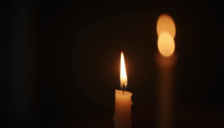 Close-up view of a candle flame flickering in a dark room, symbolizing hope and clarity