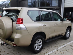 Rear view of a professionally detailed beige Toyota Land Cruiser parked outside a detailing garage, showcasing the clean exterior finish that enhances resale value.