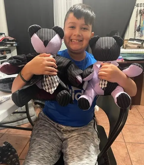 A little boy smiling holding his very own 2 memory bears by BinaBears.