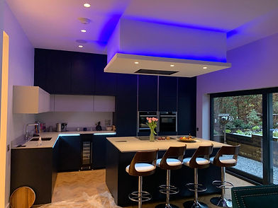 Modern kitchen with blue LED lighting, dark cabinets, and a sleek island with four barstools