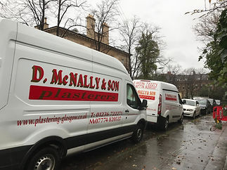 Two white McNally & Son Plasterers vans parked on a residential street