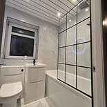 Modern white bathroom with black grid shower screen over bathtub