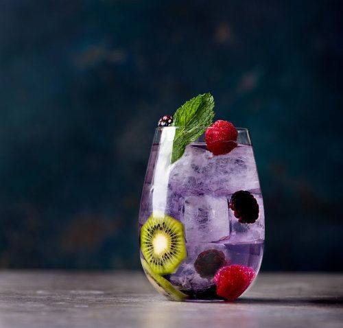 Eye-level view of a sparkling wine cocktail served in a clear glass with fresh fruit garnish on a wooden bar counter