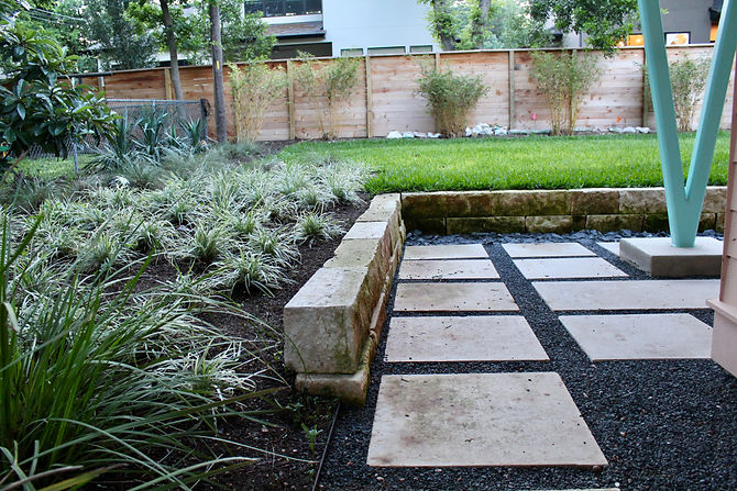 Designed by Green Eye Studios, this was a remodel done by Barley Pfeiffer Architects. The yard grading needed to be changed because the house had flooded in the past and the backyard sloped towards the house. Green Eye Studios designed a retaining wall of limestone quary blocks (the big stones) and 8" limestone dry stack. We graded everything between the house and the retaining walls with a 1" drop for every 4' so that the water would quickly run away from the house. We installed a french drain all along the wall to catch all that water and then routed it around the house to flow out to the grass in the front yard. In the front, there was a significant grade change between the yard and the street. We pulled back the grade and installed another limestone quary block wall with a small bed and walkway in front. Additionally, the original sidewalk was removed and we installed a new walkway to the entry.