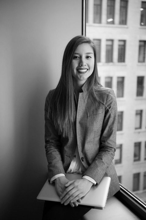 a young career woman sitting on a window box in an office
