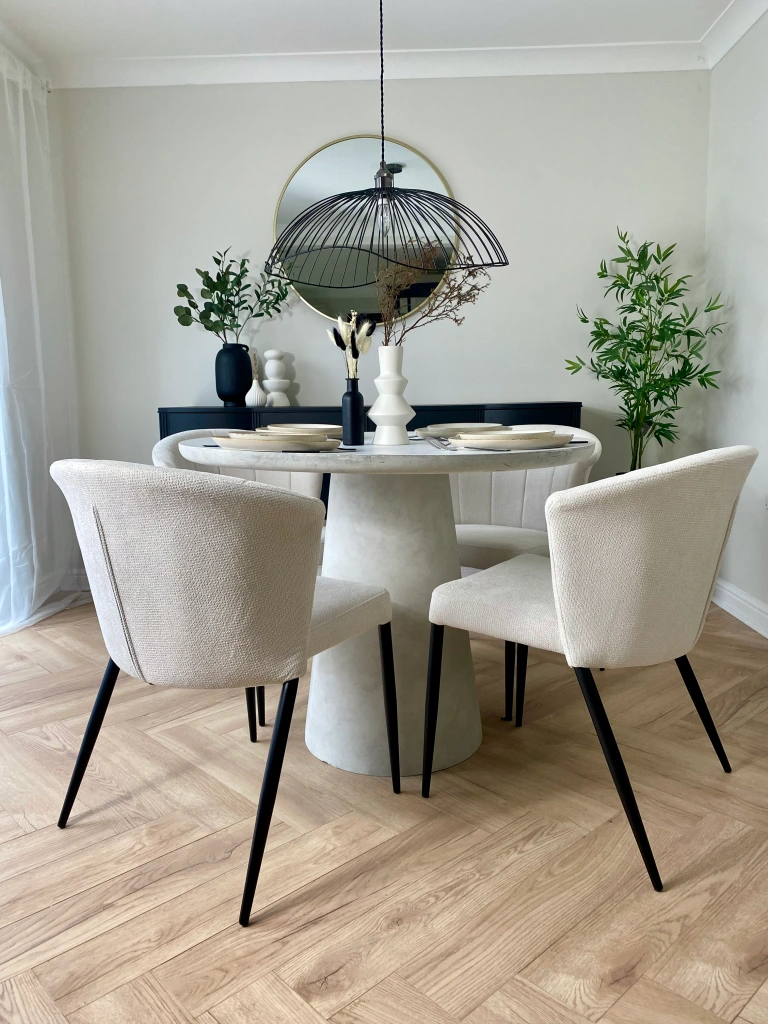 Concrete resin round dining table with white fabric chairs. Black wire ceiling light. Nordic. Scandinavian