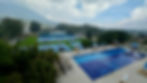 Club 14 swimming pool, pickleball courts with volcano behind. Drone photo