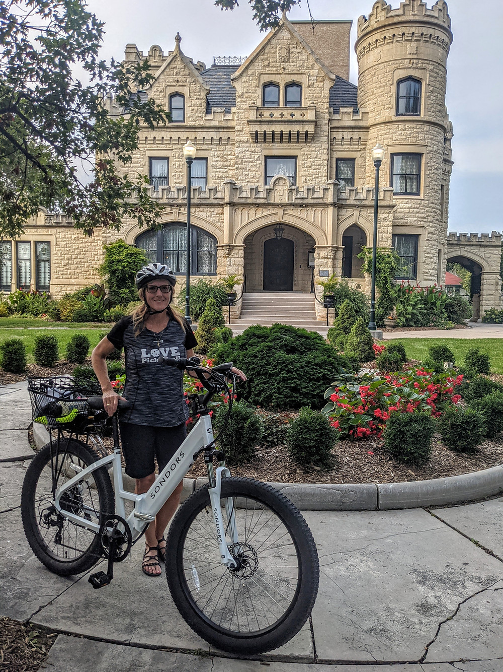 Joslyn Castle in Omaha Nebraska with woman standing in front of e-bike ebike