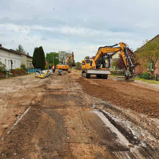 Die Straße in Ziegendorf ohne Asphalt, rechts und links stehen Häuser und in der Mitte zwei gelbe Bagger