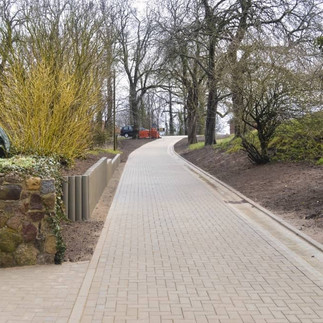 Neu gepflasterter Anwohnerweg inmitten durch kahle Bäume.