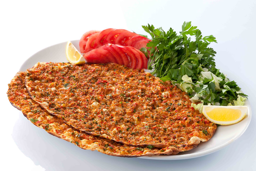 Beyaz tabakta lahmacun, domates dilimleri, maydanoz ve limon; sade arka planda iştah açıcı sunum.