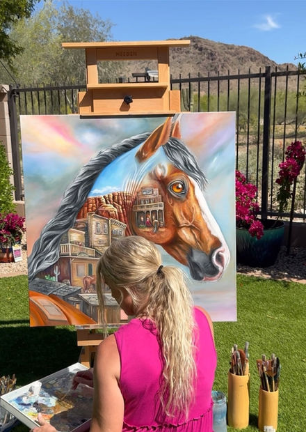 Western Echoes oil painting by Dani Abbott displayed outdoors beside a wrought-iron fence.