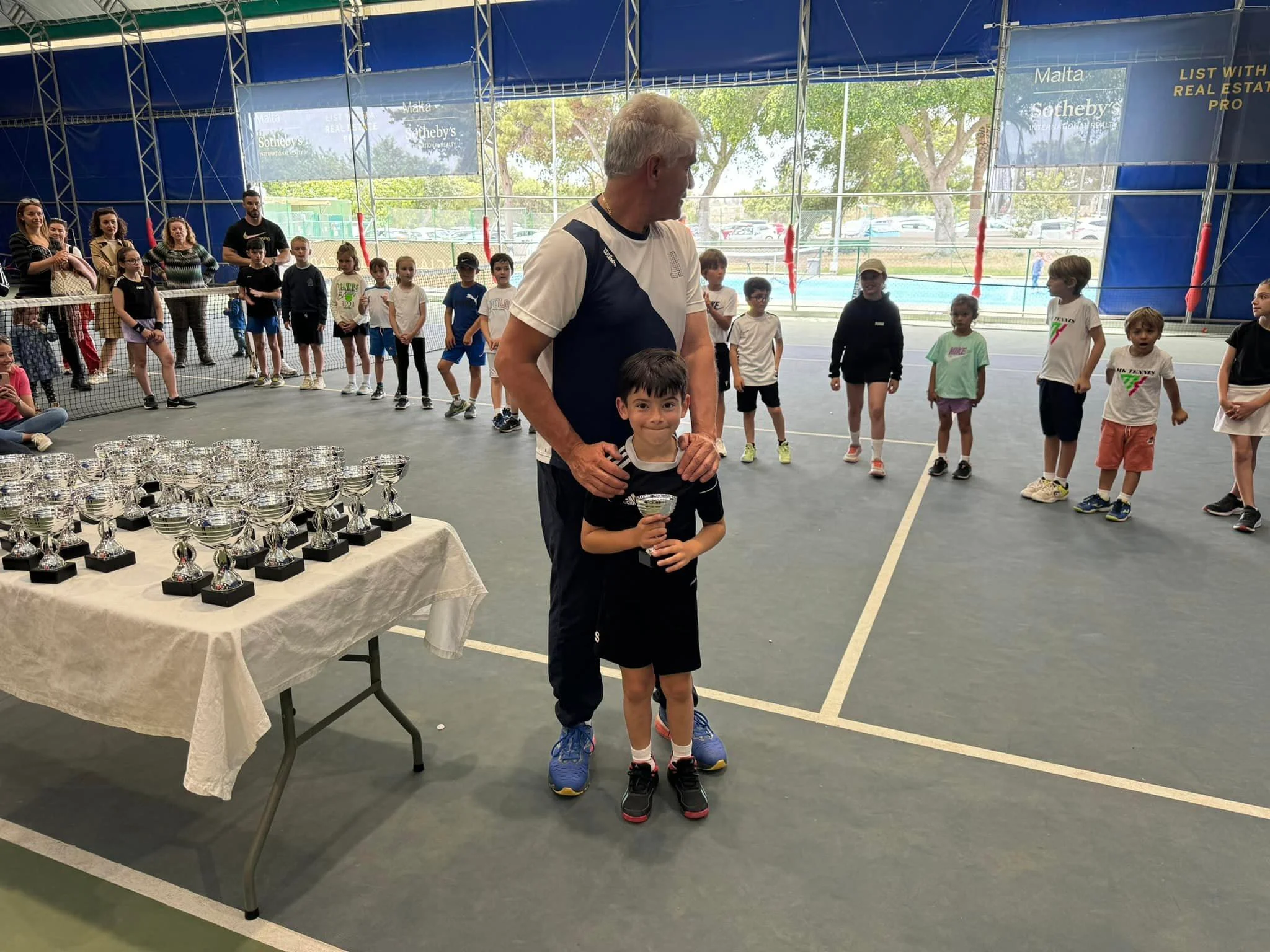 Tennis kid with trophy and coach