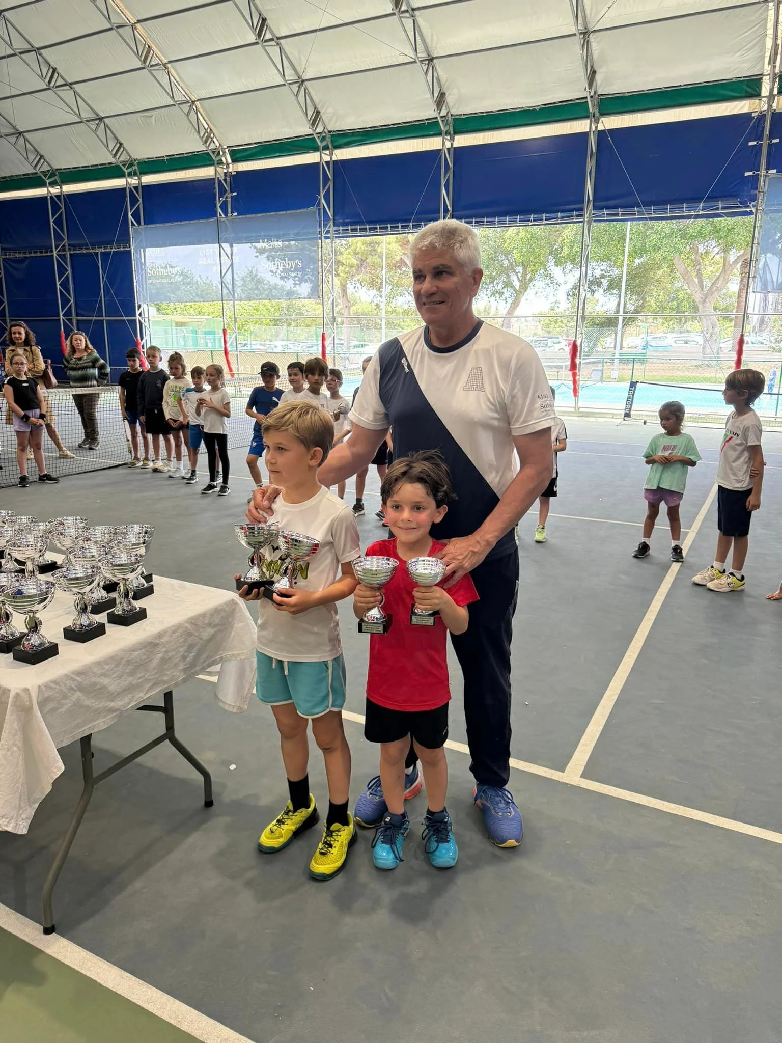 Tennis kids with trophy and coach
