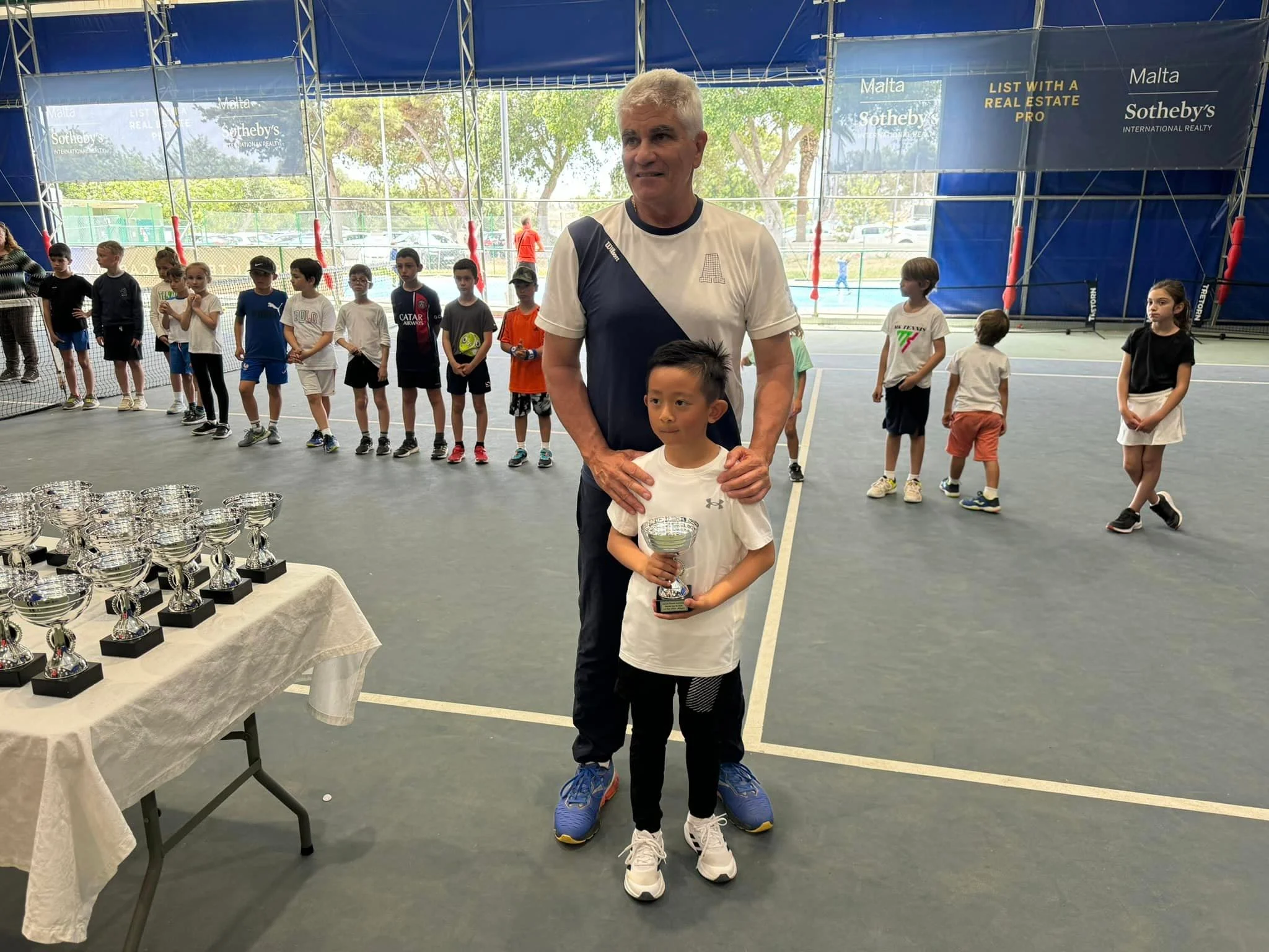 Tennis kid with trophy and coach