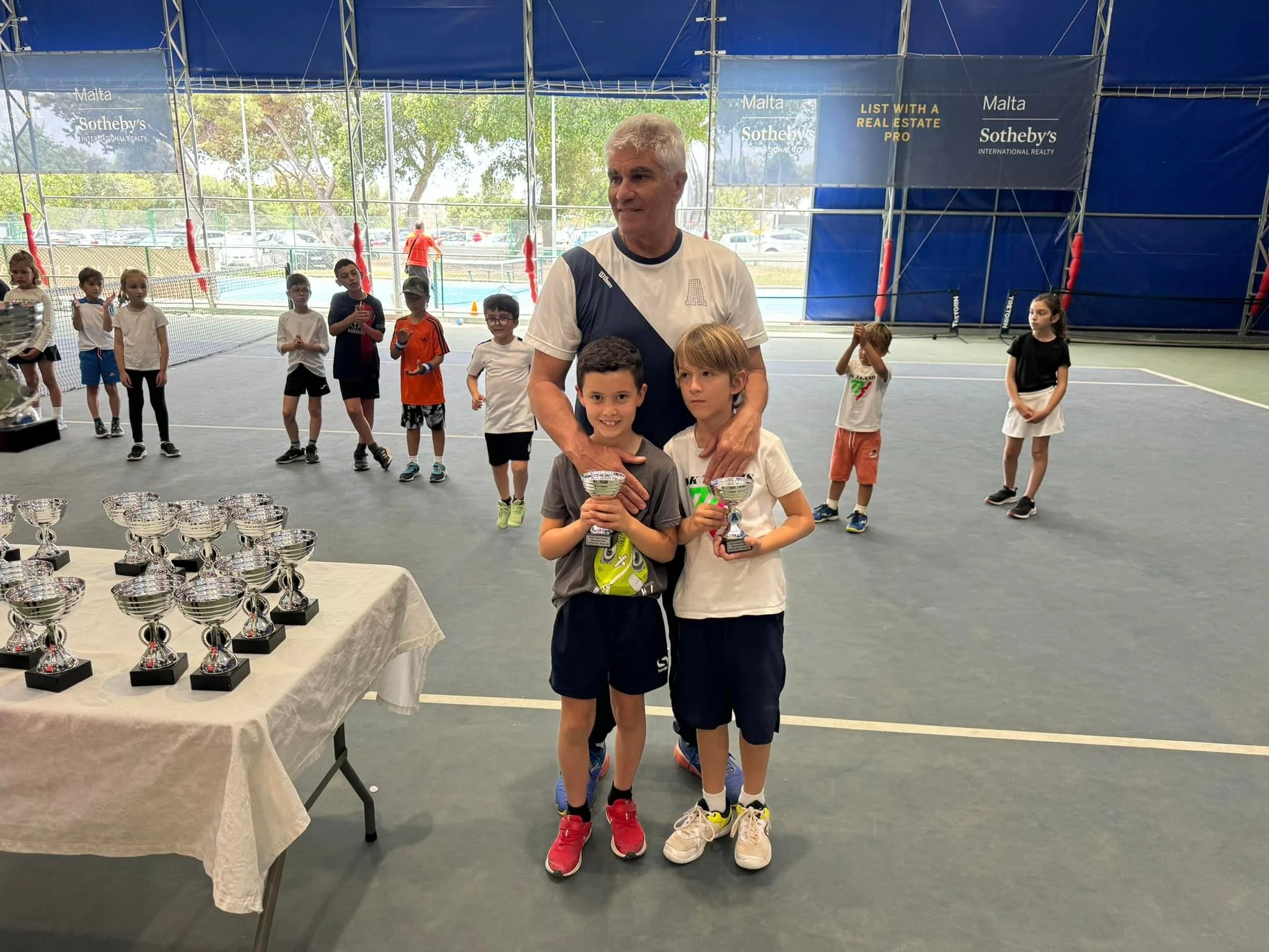 Tennis kids with trophy and coach