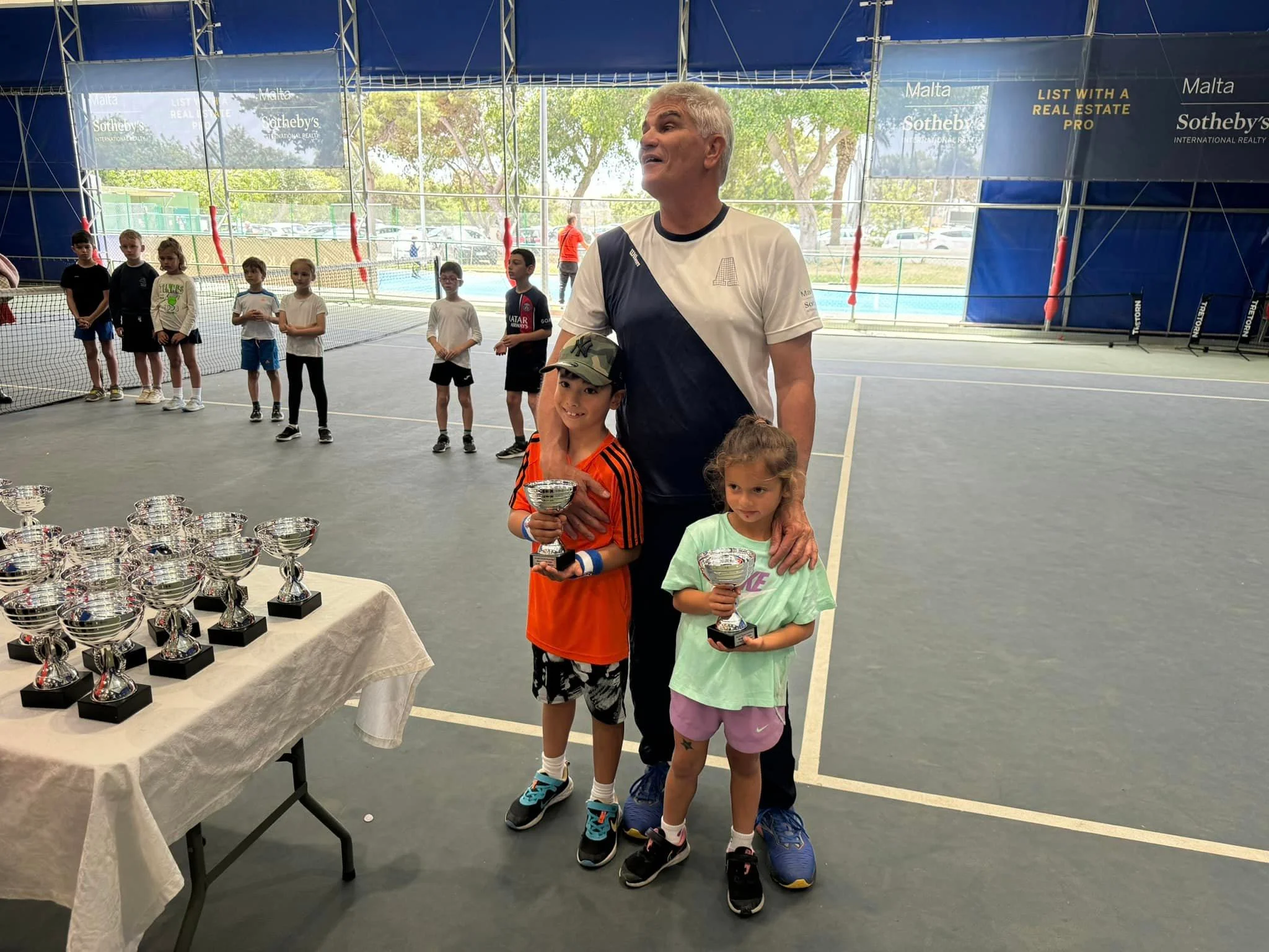 Tennis kids with trophy and coach