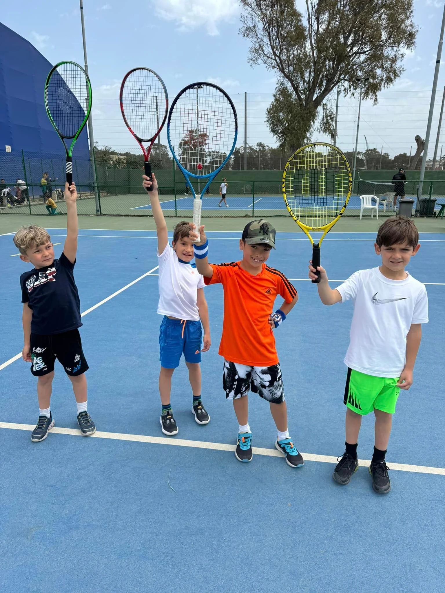 Tennis kids holding up rackets