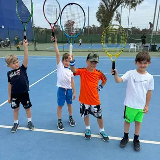 Tennis kids holding up rackets