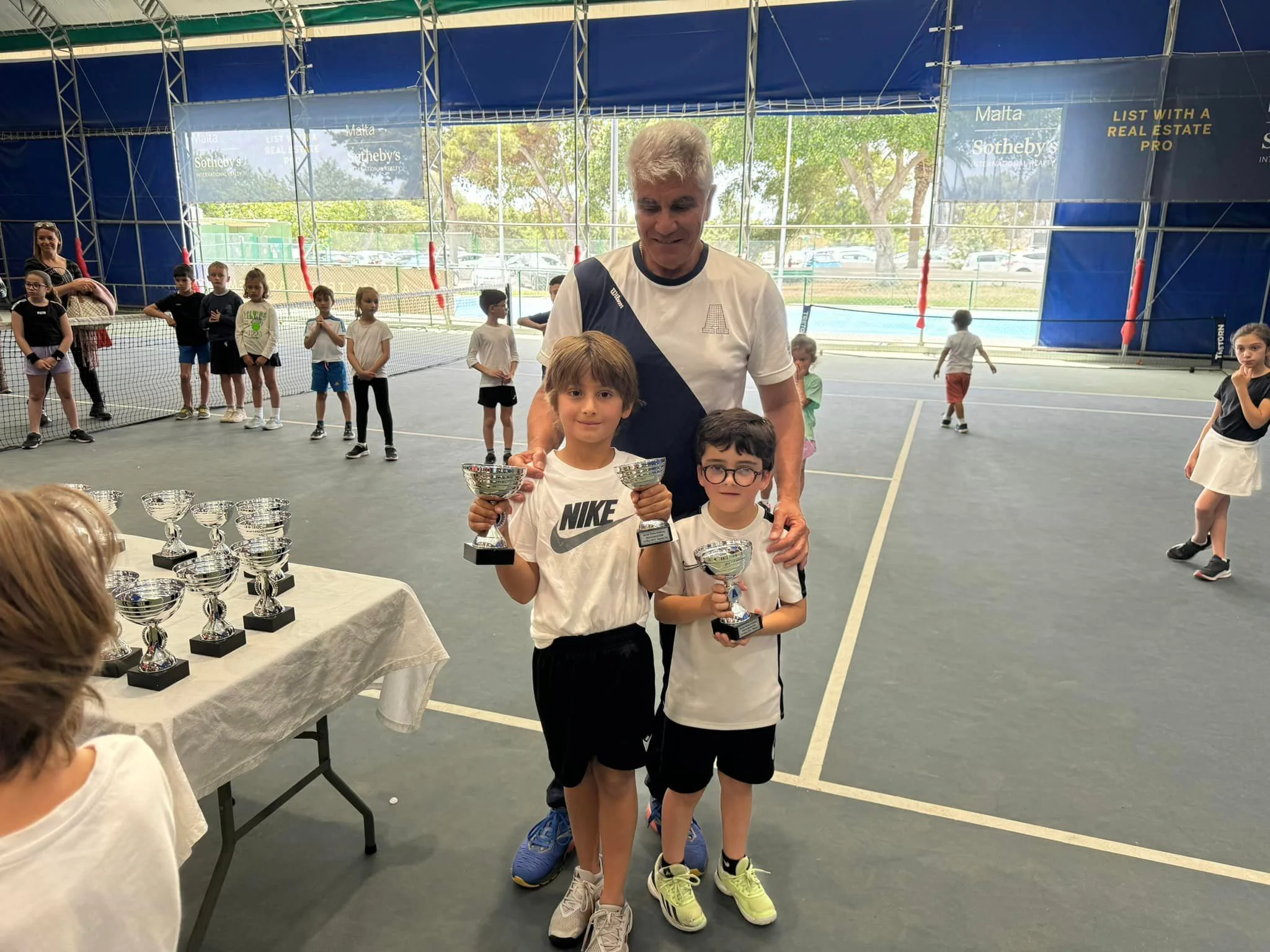 Tennis kids with trophy and coach