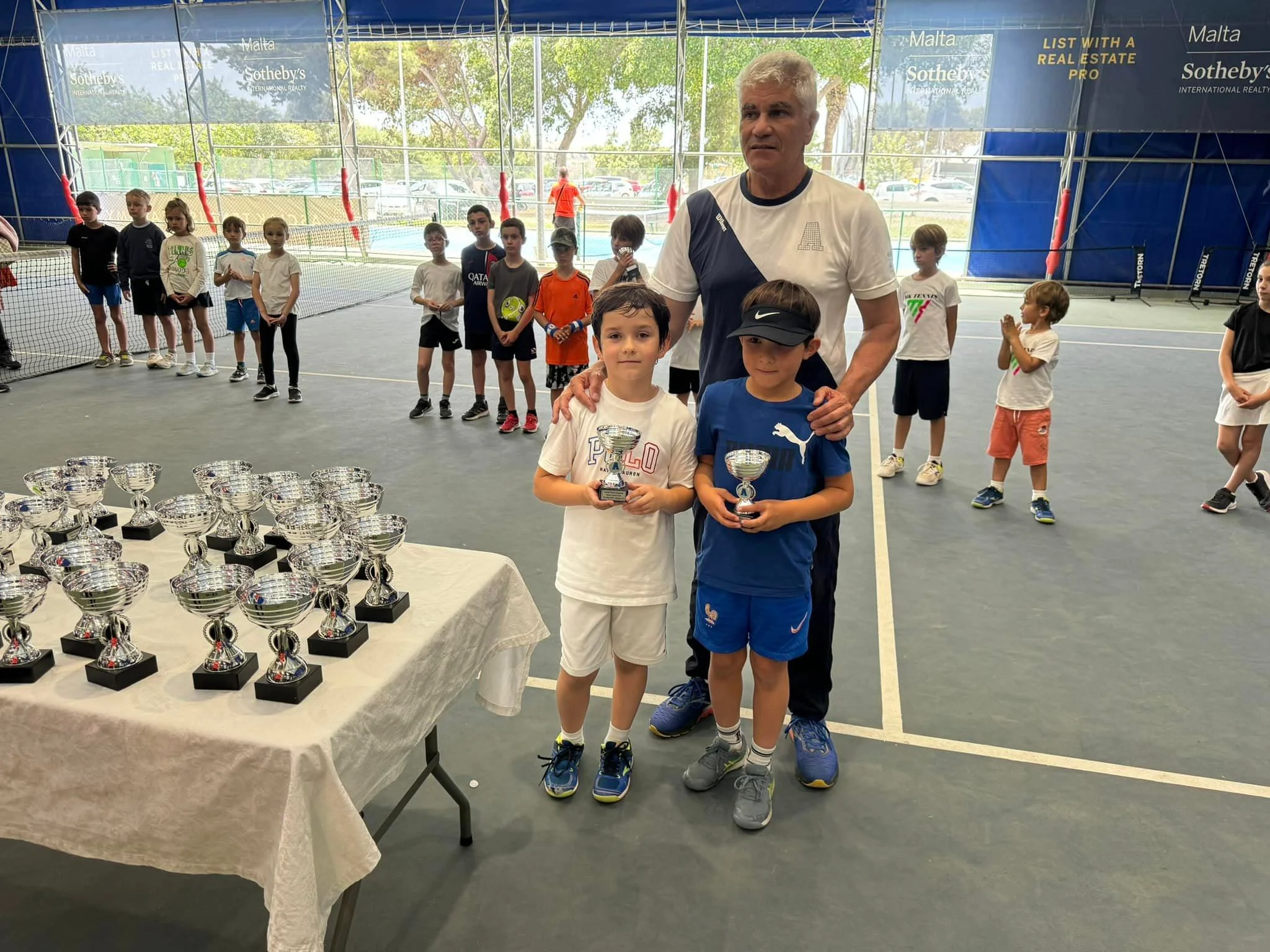 Tennis kids with trophy and coach