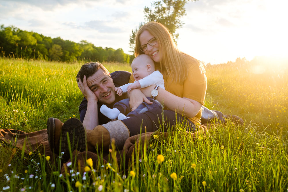 Familie sitzt mit Baby auf einer Wiese
