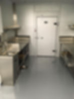 Commercial kitchen: stainless steel counters, walk-in refrigerator, and epoxy floor