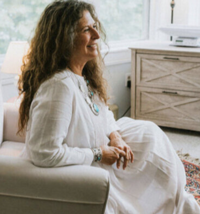 Katherine Bramhall, CPM, smiling and sitting in a chair