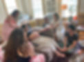 Sacred Openings' owner, birth and postpartum doula, Kayla Brookins, massaging a mom's feet during her Mother Blessing Ceremony, while her family and friends massage her hands and head.