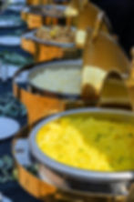 Gold chafing dishes with rice, proteins, and sides set up for buffet-style catering service