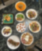 A large spread of various plated appetizers and main courses, including shrimp, salads, and charcuterie items, arranged on a