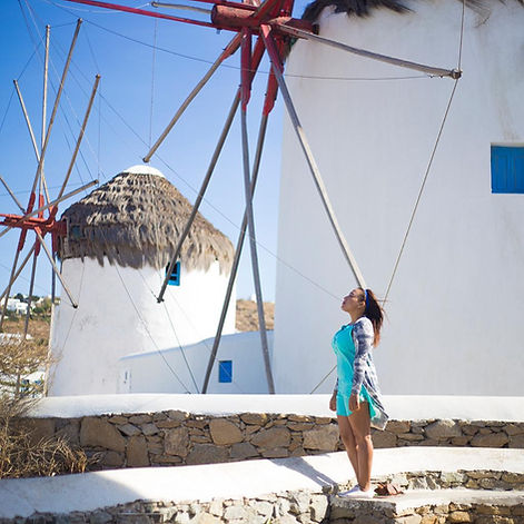 "Iconic windmills of Mykonos overlooking the Aegean Sea with traditional white buildings in the background"