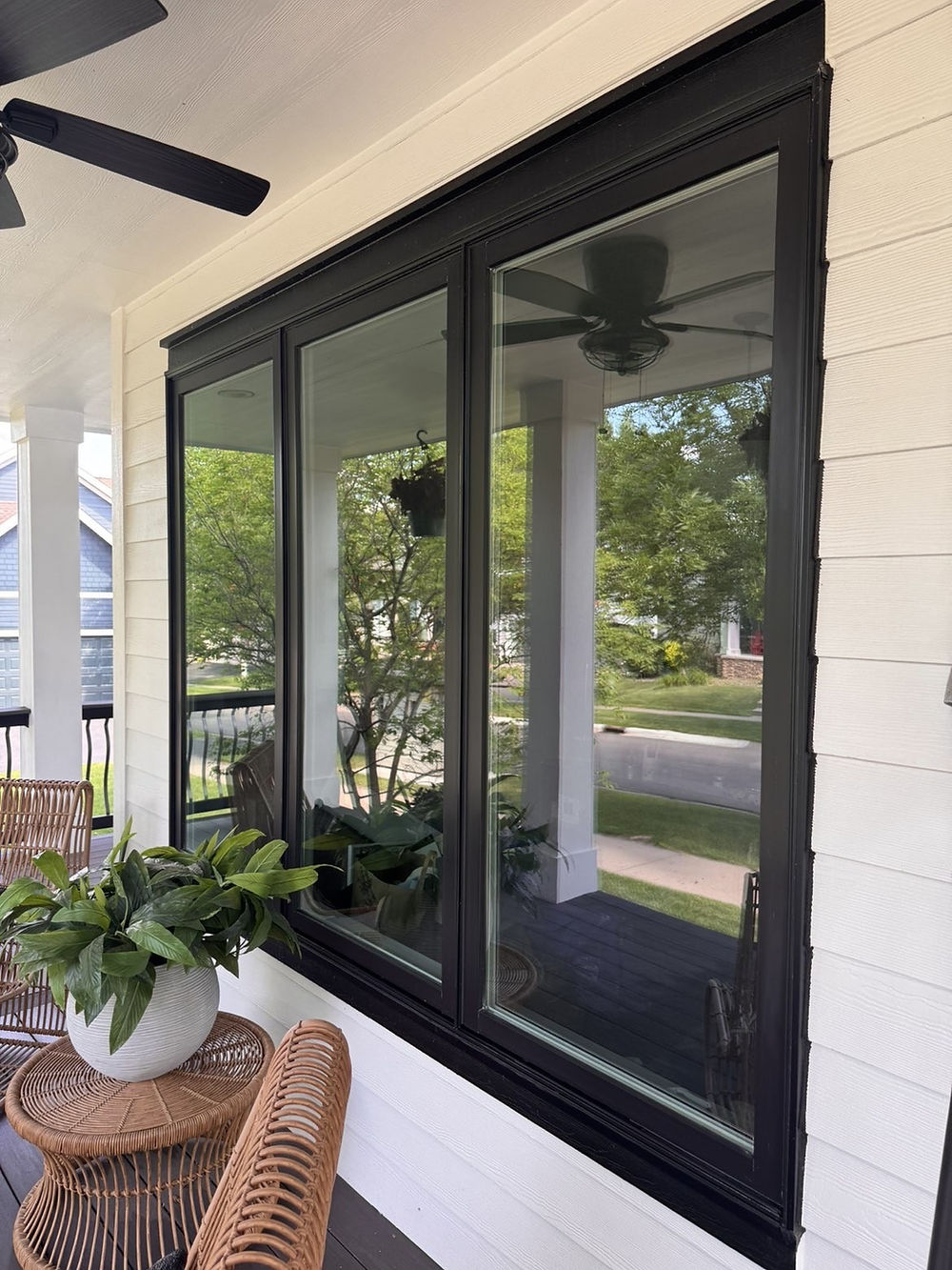 Clean windows reflecting the porch and trees after window cleaning.