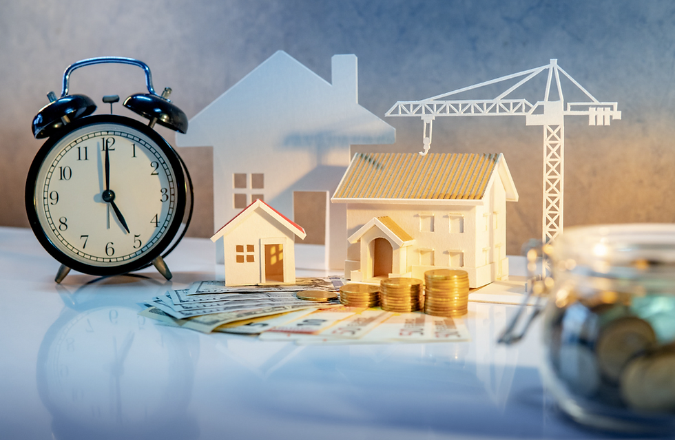 Makieta domów i budynków z dźwigiem budowlanym, zegar symbolizujący upływ czasu oraz monety i banknoty, ilustrujące sprzedaż nieruchomości i jej skutki podatkowe w VAT.