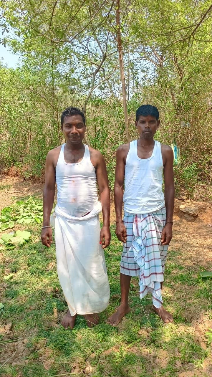 Men dressed in vest and dhoti near the mountain — the prescribed ritual attire. The Dehri of the village stands on the left. Edelbera, April 2026. Motu Mahali and Damu Mahali (L to R)
