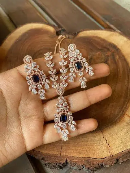 Elegant rose gold necklace and earrings set with blue sapphires and white cubic zirconia.