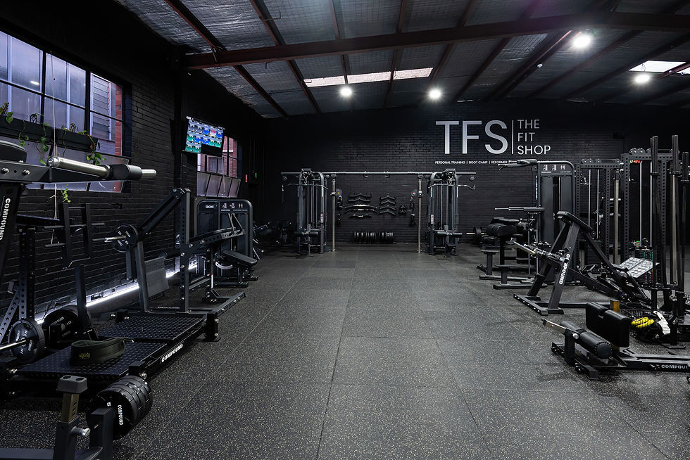 Gym interior with exercise equipment, TFS THE FIT SHOP logo on wall.
