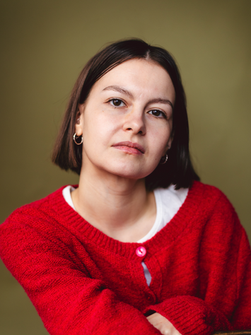 Actor headshot of a woman in a red cardigan in front of a green backdrop in a manchester based studio setting