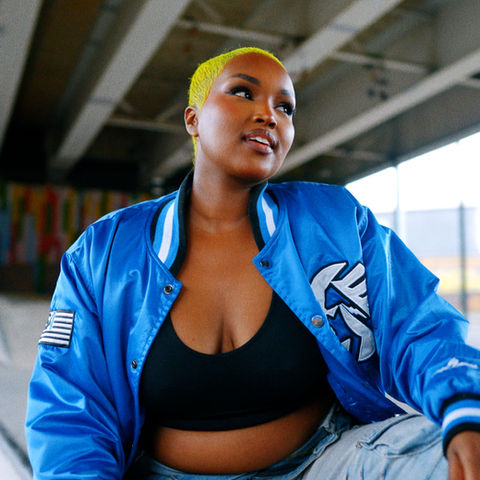 screenshot from a video of a Woman with bold, colourful style and fashion posing in a skatepark looking off camera.