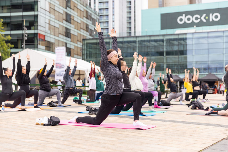 Group shot of people enjoying an outdoor yoga session in Media City, Salford