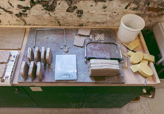 Birds Eye view image of a workshop table with lots of clay and tools on it