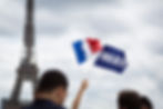 Des manifestants à Paris brandissent un drapeau français et un drapeau bleu marqué "Frexit", symbolisant le soutien à une campagne pour la sortie de la France de l'Union européenne, avec la tour Eiffel en arrière-plan.