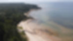 Aerial drone shot of a coastline with a beach and forest