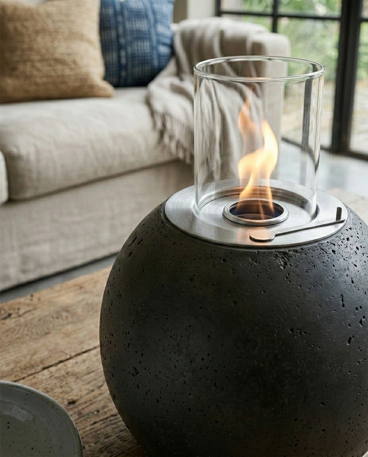 Küre biçimli koyu gri beton şömine, alevli, rahat oturma odası.