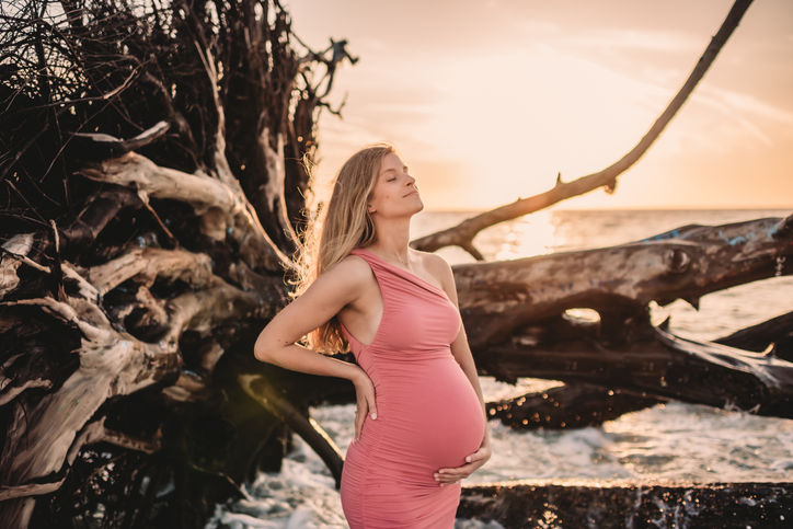 Pregnant mother on beach taking a deep breath