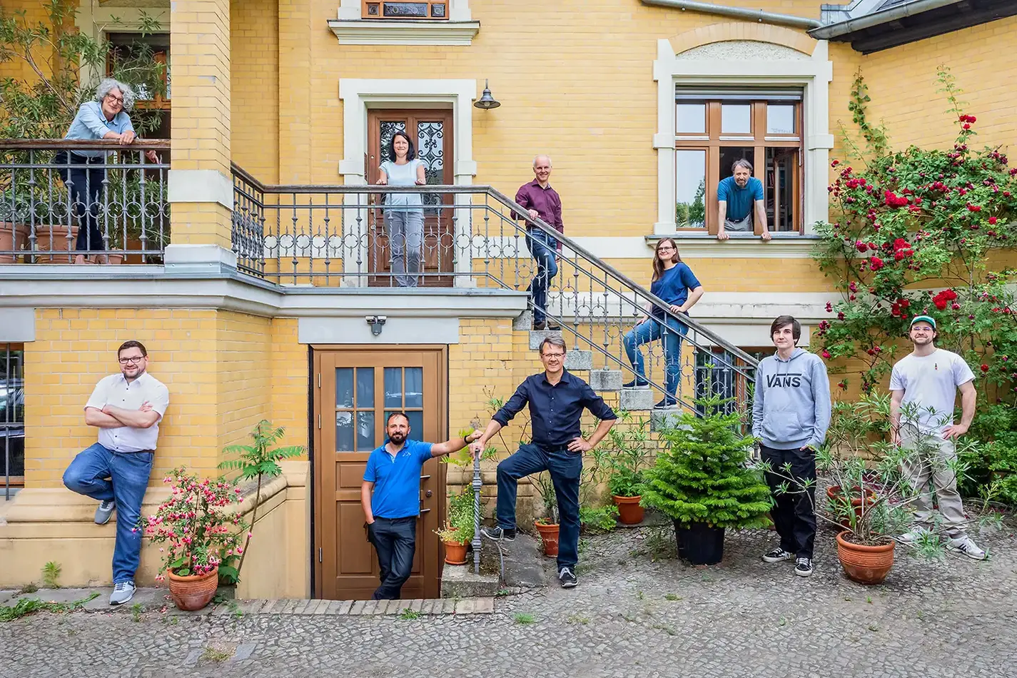 Eine Gruppe von Kolleginnen und Kollegen posiert für ein Business Portrait Berlin vor einem historischen Gebäude mit Garten, betont Teamgeist und Authentizität.