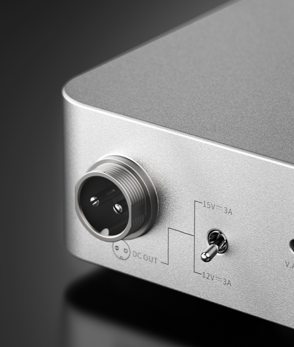 Close-up of a silver device panel with a round power connector, toggle switch, and labels DC OUT, 15V 3A, and 12V 3A.